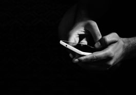 grey scale photo of person holding smartphone