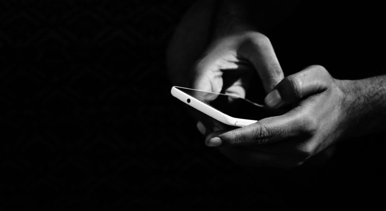 grey scale photo of person holding smartphone