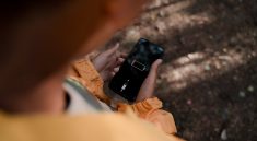 teenage boy holding smart phone with low battery in forest
