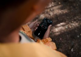 teenage boy holding smart phone with low battery in forest
